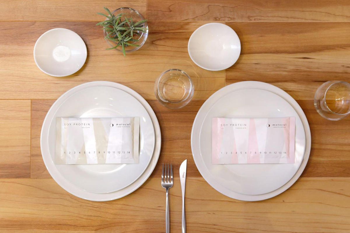 2枚の皿に置かれた、妊活プロテイン motoculの2種類の個包装パッケージ